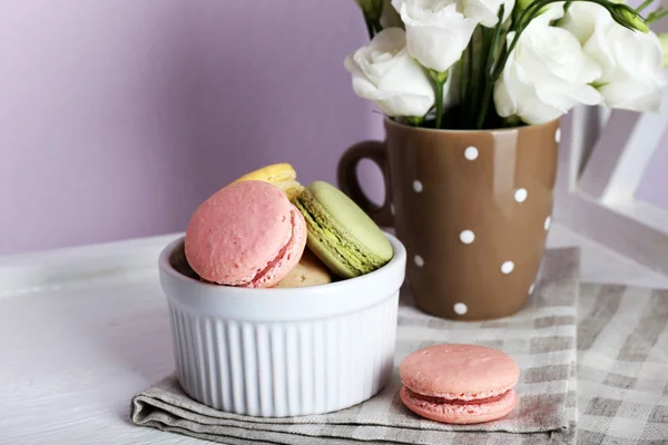 Delicious macaroon with beautiful flowers on light background — Stock Photo, Image