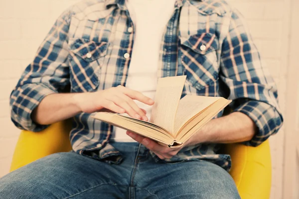 Junger Mann liest Buch, Nahaufnahme, auf hellem Hintergrund — Stockfoto