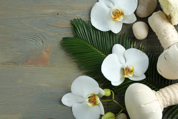 Bodegón con hermosa flor de orquídea, tratamiento de spa y guijarros, sobre fondo de madera — Foto de Stock
