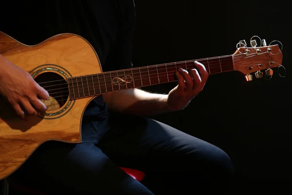 어두운 배경에서 어쿠스틱 기타로 연주하는 소년 — 스톡 사진