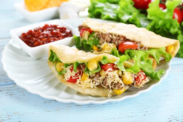 Tasty taco with tomato dip on plate and vegetables on table close up — Stock Photo, Image