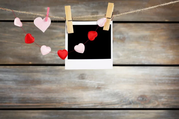 Bright hearts and photo paper hanging on rope on wooden background — Stock Photo, Image