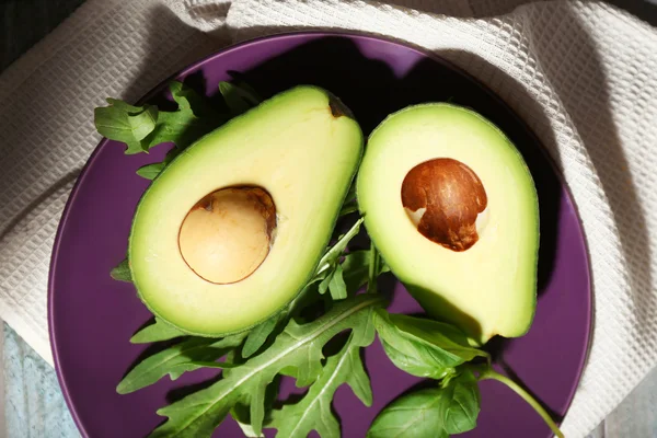 Sliced avocado, arugula on wooden background — Stock Photo, Image