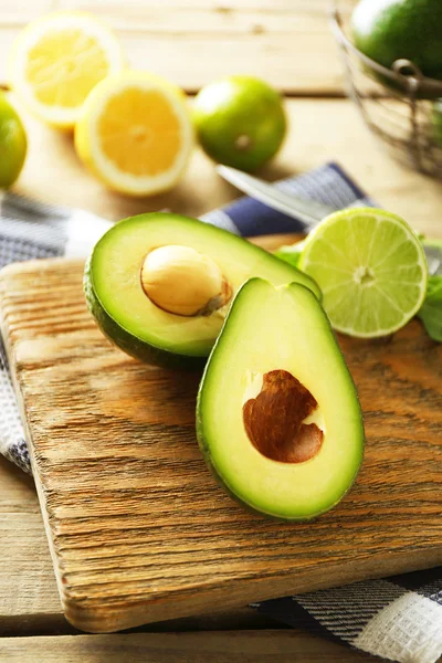 Avocado affettato e lime limone sul tagliere, su fondo di legno — Foto Stock