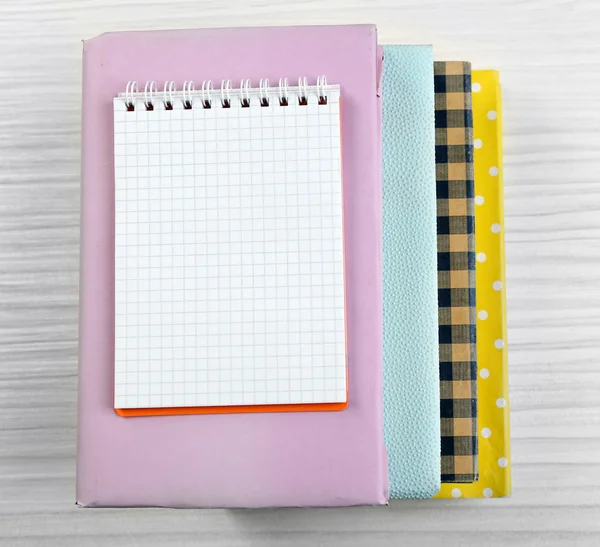 Notebook on top of pile of books and magazines on wooden background — Stock Photo, Image