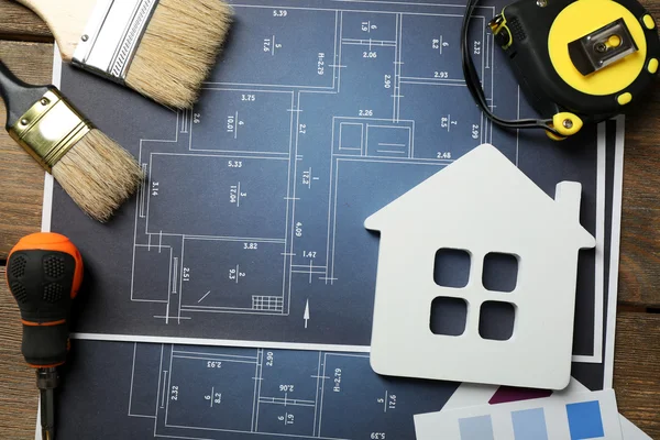 Farbmuster, dekoratives Haus, Handschuhe und Pinsel auf Holztischhintergrund — Stockfoto