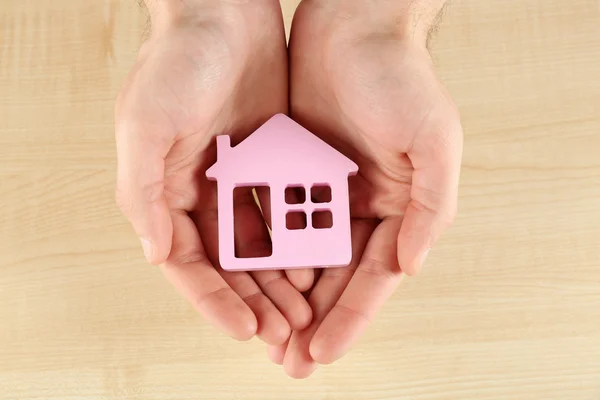 Female hands holding house on wooden background — Stock Photo, Image