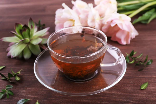 Cup of herbal tea with tulips on wooden table, closeup — Stock Photo, Image