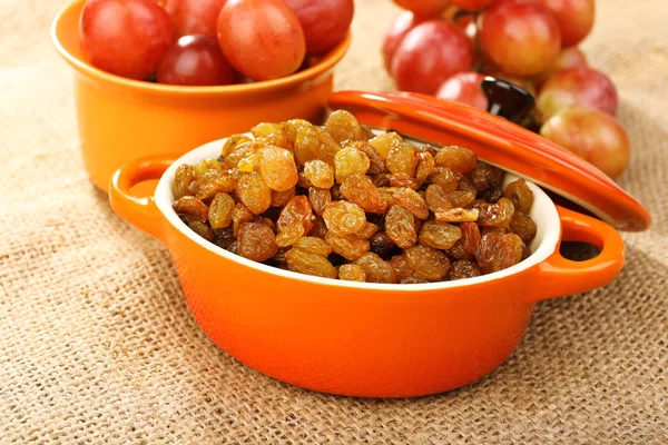 Raisins in bowl with grapes on table close up — Stock Photo, Image