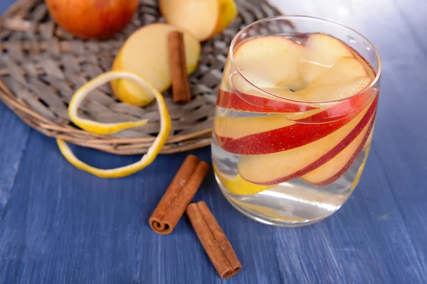 Glass of apple cider with fruits and cinnamon on table close up — Stock Photo, Image