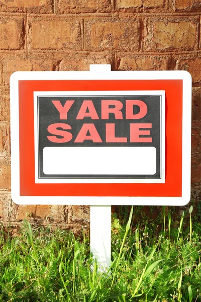 Деревянный двор Продажа знак в зеленой траве на фоне стены из красного кирпича — стоковое фото
