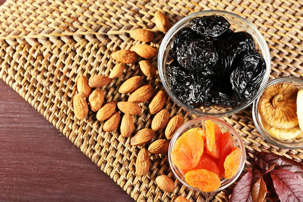Poda e outras frutas secas com folhas de uva no tapete de vime, close-up — Fotografia de Stock