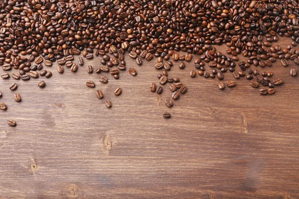 Grãos de café em fundo de madeira — Fotografia de Stock