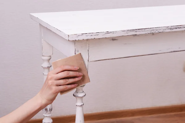Женская рука снимает краску с деревянного стола для украшения, внутри помещений — стоковое фото