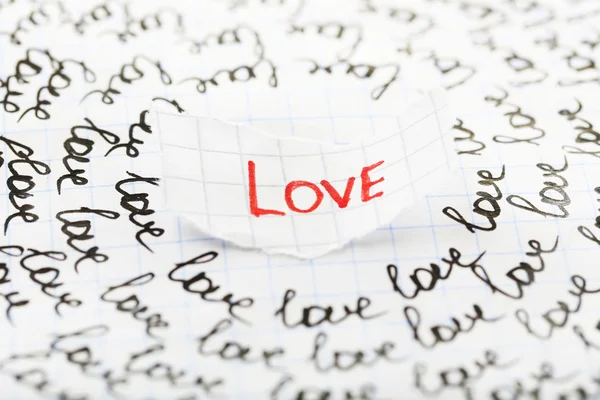 Word LOVE written on torn paper on sheet of paper background — Stock Photo, Image