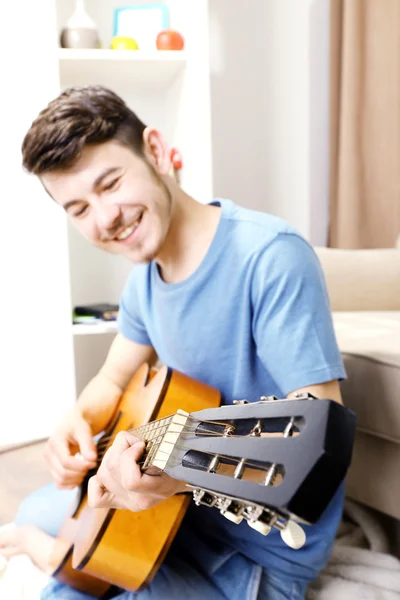 Giovane con chitarra al piano in camera — Foto Stock