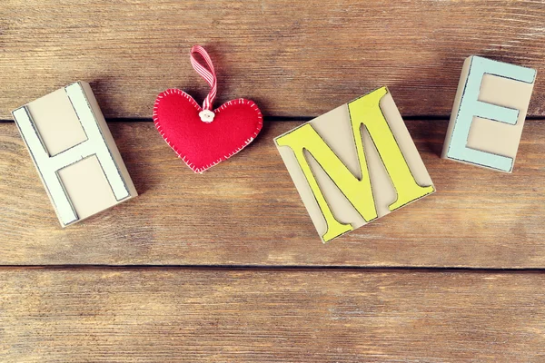 Lettres décoratives formant mot HOME avec coeur décoratif sur fond en bois — Photo
