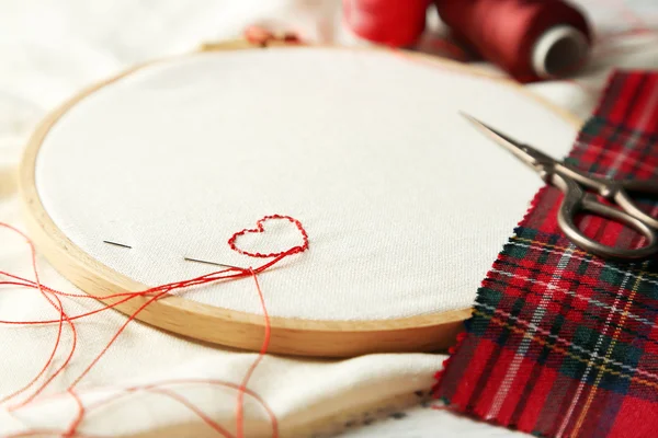 El aro de bordado con tela e hilos de coser rojos en la mesa de cerca — Foto de Stock