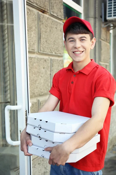 Jovem entregando caixa de pizza perto de casa — Fotografia de Stock