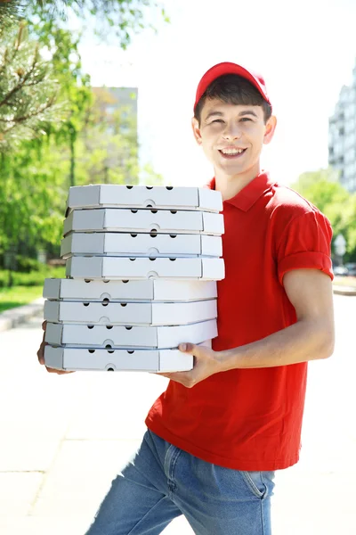 Młody człowiek dostarczający pizzy pole na zewnątrz — Zdjęcie stockowe