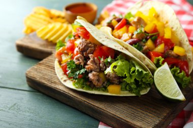ahşap arka plan üzerinde kesme tahtası üzerinde ev yapımı sığır eti burrito sebzeli patates cips