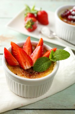 Creme brulee tatlısı peçeteye renk ahşap arka plan üzerinde taze çilek Çilek ile