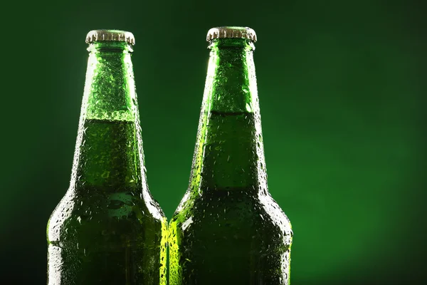 Botellas de vidrio de cerveza sobre fondo verde oscuro — Foto de Stock