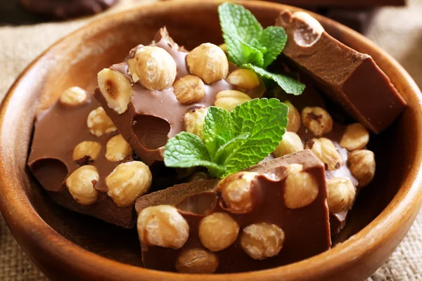 Pyszne czekolady z orzechami i liści mięty w misce, zbliżenie — Zdjęcie stockowe