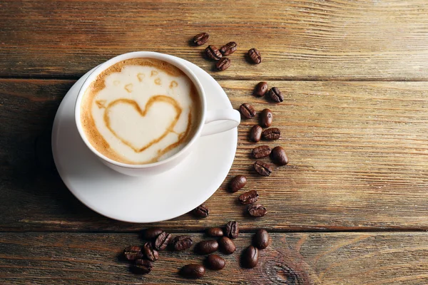 Kopp kaffe latte art med korn på trä bakgrund — Stockfoto