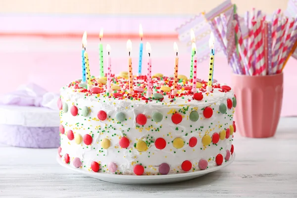 Tarta de cumpleaños con vela sobre fondo a rayas de colores —  Fotos de Stock