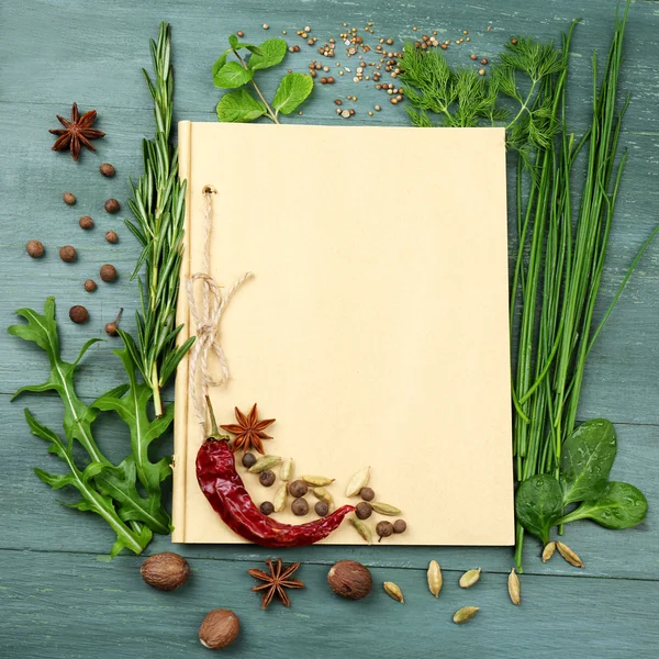 Livro de receitas aberto com ervas frescas e especiarias em fundo de madeira — Fotografia de Stock