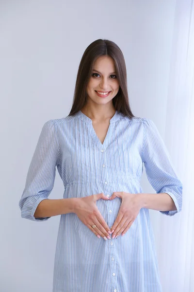 Zwangere vrouw op witte muur achtergrond, binnenshuis — Stockfoto