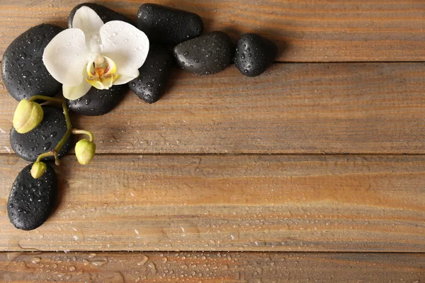 Spa stones and orchid flower on wooden background — Stock Photo, Image