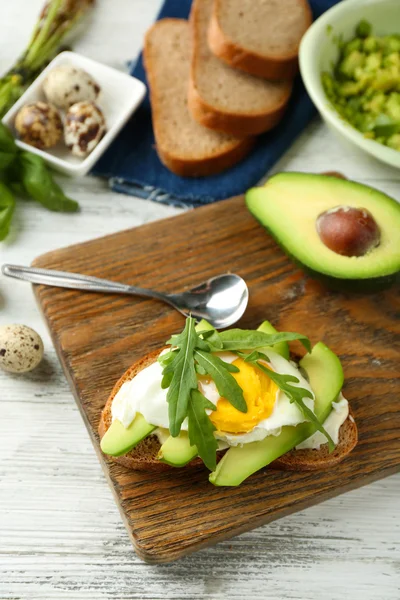 Вкусный сэндвич с яйцом, авокадо и рукколой на деревянном фоне — стоковое фото