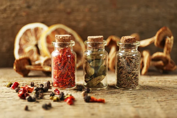 Assortiment van specerijen in glazen flessen op houten achtergrond — Stockfoto