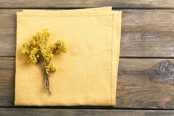 Bellissimi fiori secchi su tovagliolo su sfondo di legno — Foto Stock