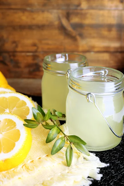 Still life with lemon juice and sliced lemons on wooden background