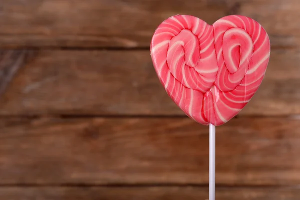Bright lollipop in shape of heart on wooden background — Stock Photo, Image