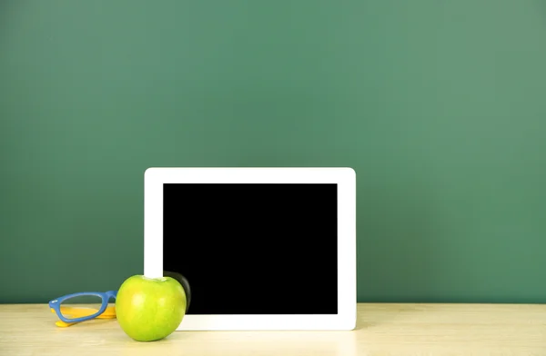 Tablet na mesa, em fundo quadro-negro verde — Fotografia de Stock