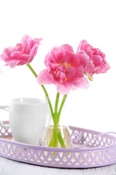 Pink tulips in glass vase with cup on tray, isolated on white — Stock Photo, Image