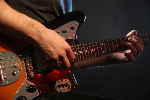 Young man playing on electric guitar on dark background — Stock Photo, Image