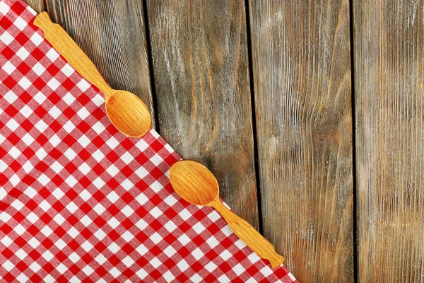 Guardanapo xadrez com colheres em fundo de mesa de madeira — Fotografia de Stock