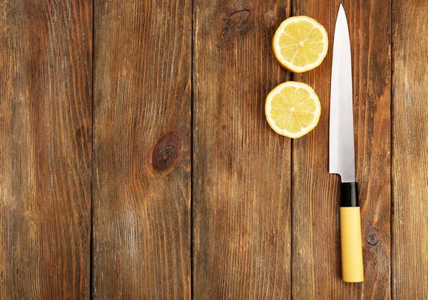 Halves of lemon with knife on wooden background — Stock Photo, Image