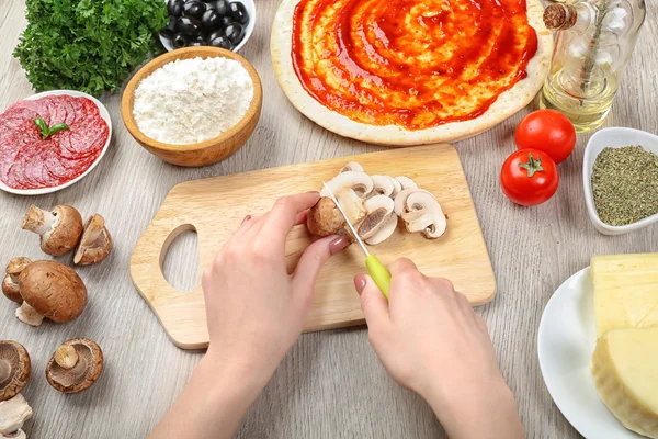 Mani femminili che cucinano la pizza sul tavolo di legno, primo piano — Foto Stock