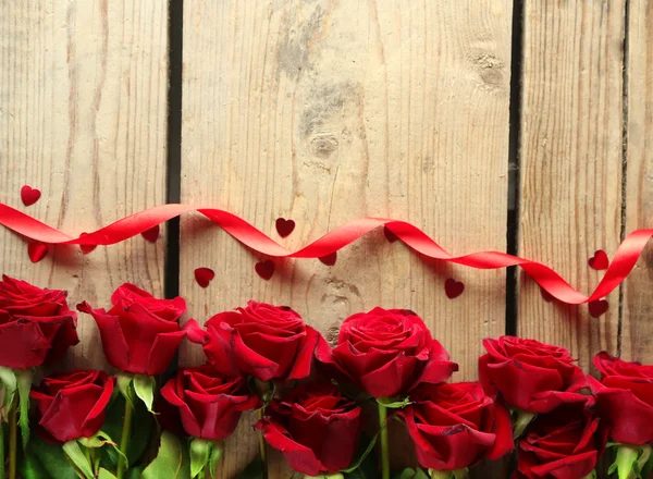 Piękne czerwone róże na starym drewnianym stole — Zdjęcie stockowe