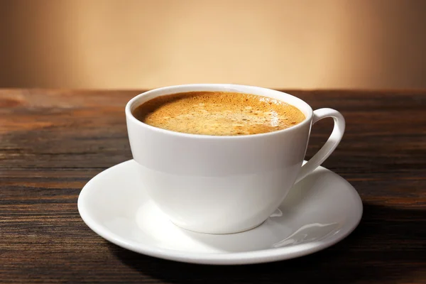 Taza de café en la mesa sobre fondo marrón —  Fotos de Stock