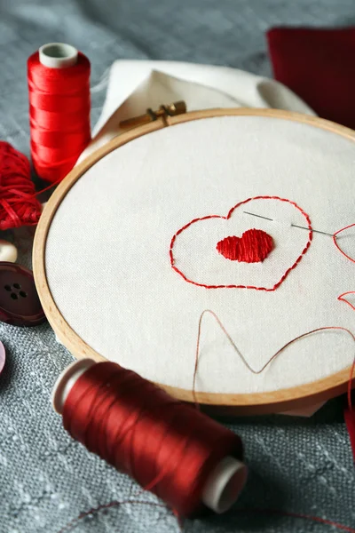 El aro de bordado con tela e hilos de coser rojos en la mesa de cerca — Foto de Stock