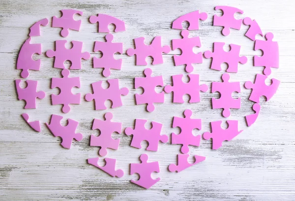 Coeur de puzzle rose sur fond en bois — Photo