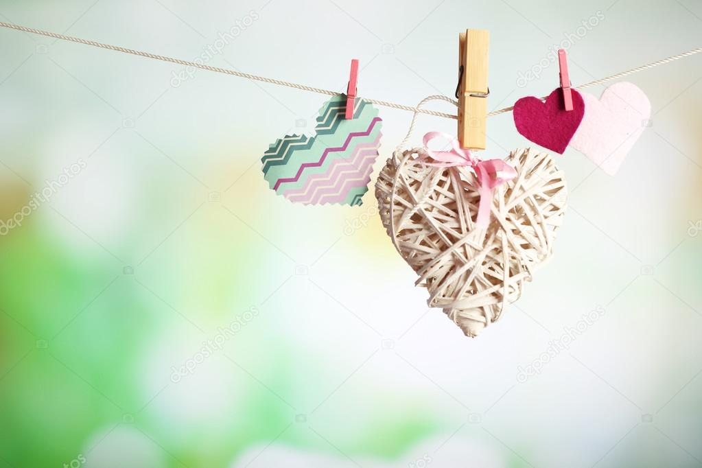 Hearts hanging on rope on bright background