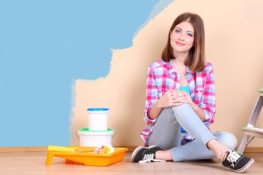 Güzel kız boyama duvar için ekipman ile yerde yatarken